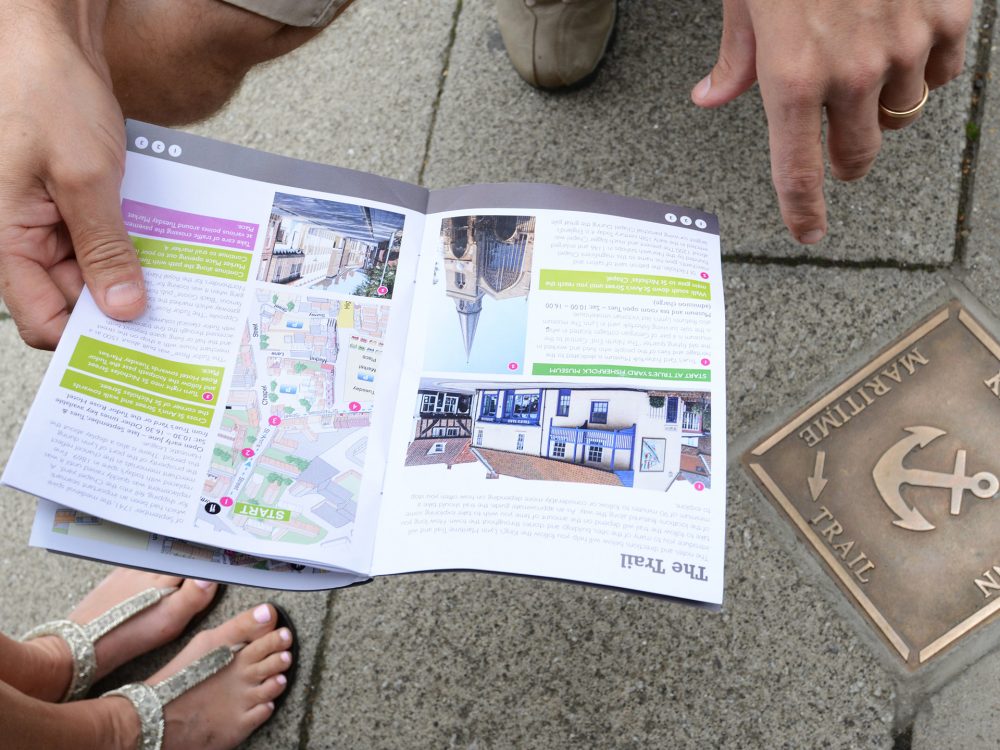 A woman sat on a coach looking at the camera, wearing a hat and sunglasses.