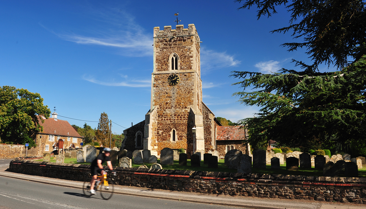 A man riding on a bike near a church in a west Norfolk village.