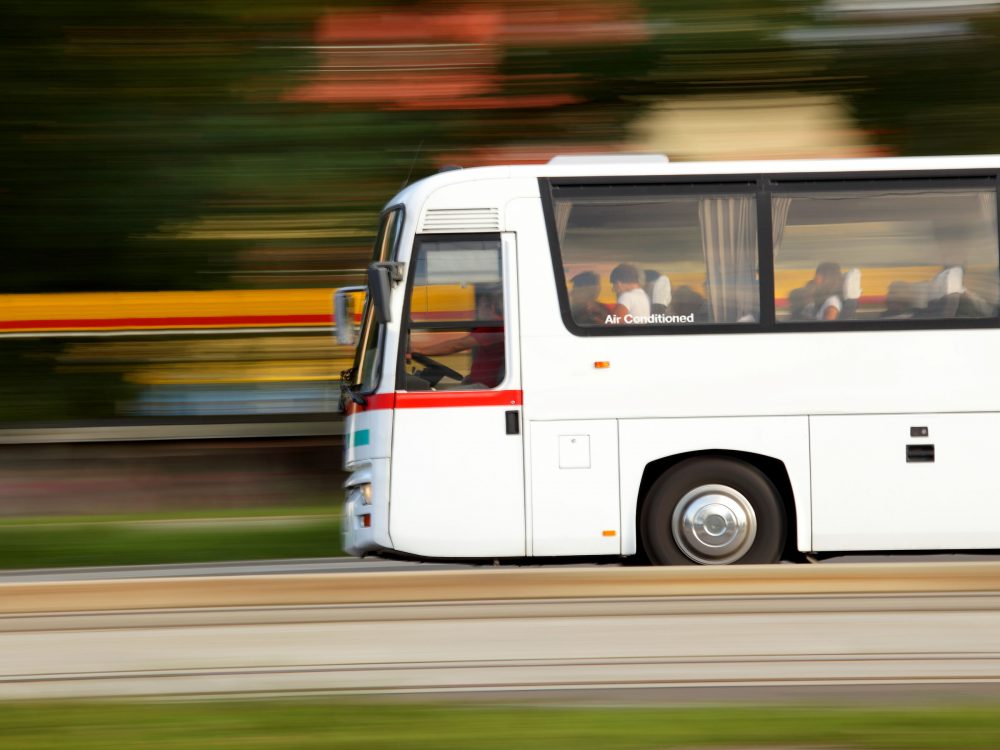 A white coach driving down the road at a fast speed. The bus has a sign that states 
