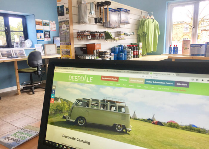 Inside the Deepdale Visitor Information Centre with a computer screen of the "Deepdale Camping" page.