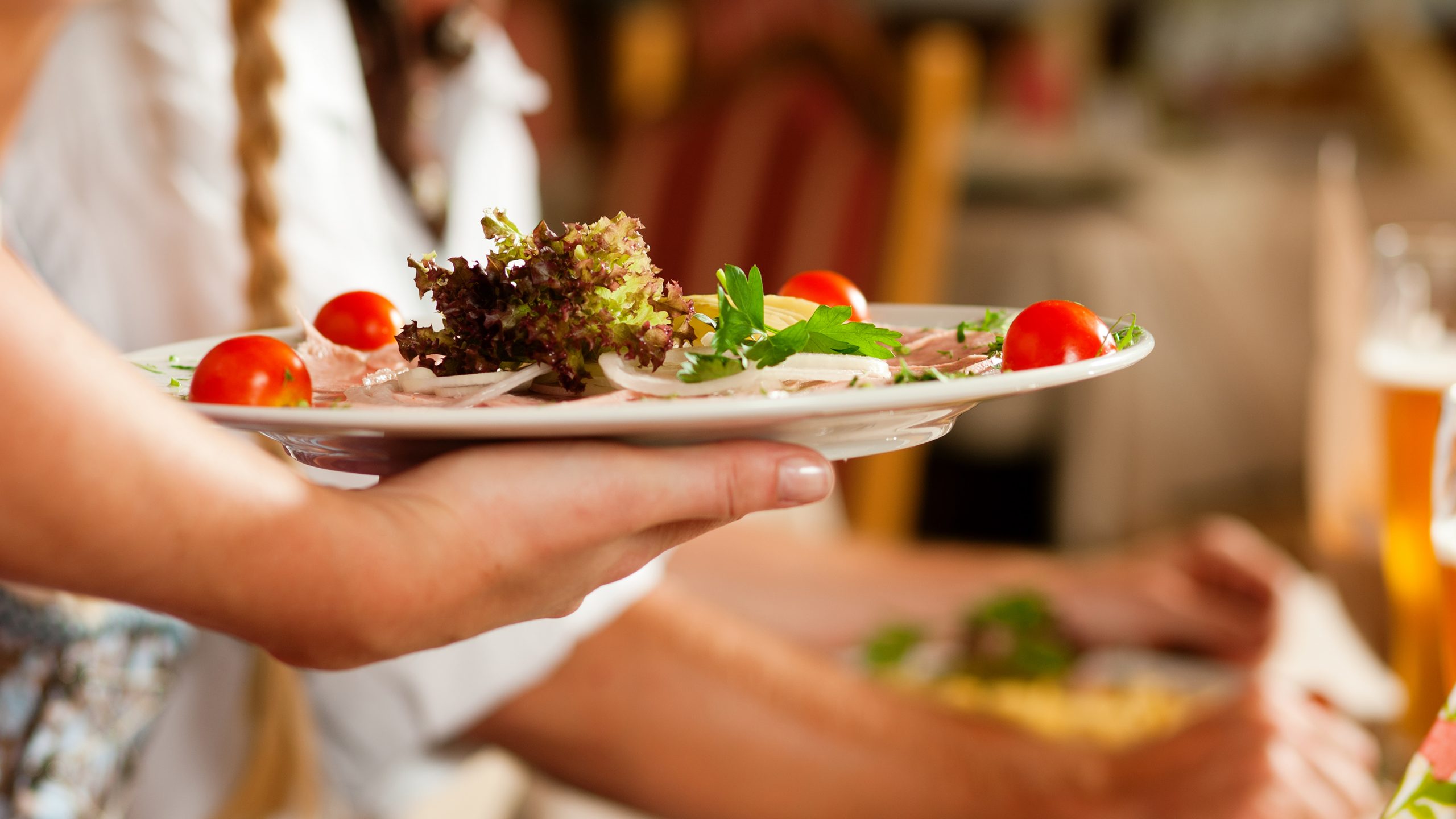 A server holding a plate of food to a table.