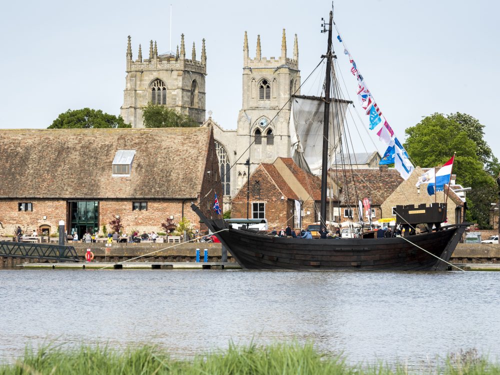 Hanse Day celebrations on Boal Quay in King's Lynn with a docked shit sitting in front of the Marriotts Warehouse. The King's Lynn Minster can be seen standing tall in the background.