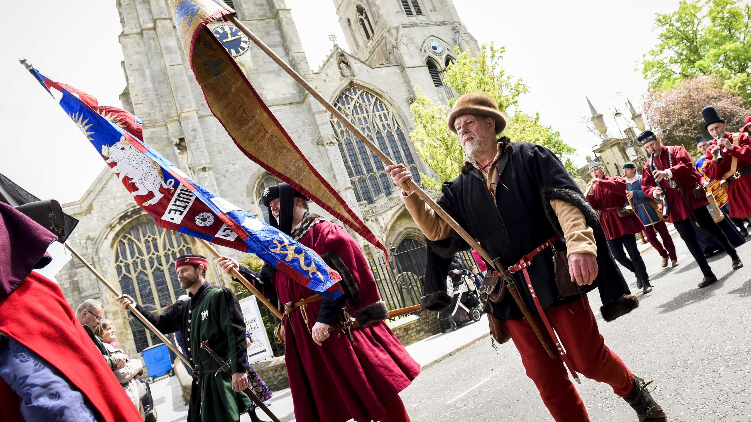 A man waving a hanseatic flag in front of King's Lynn Minster.