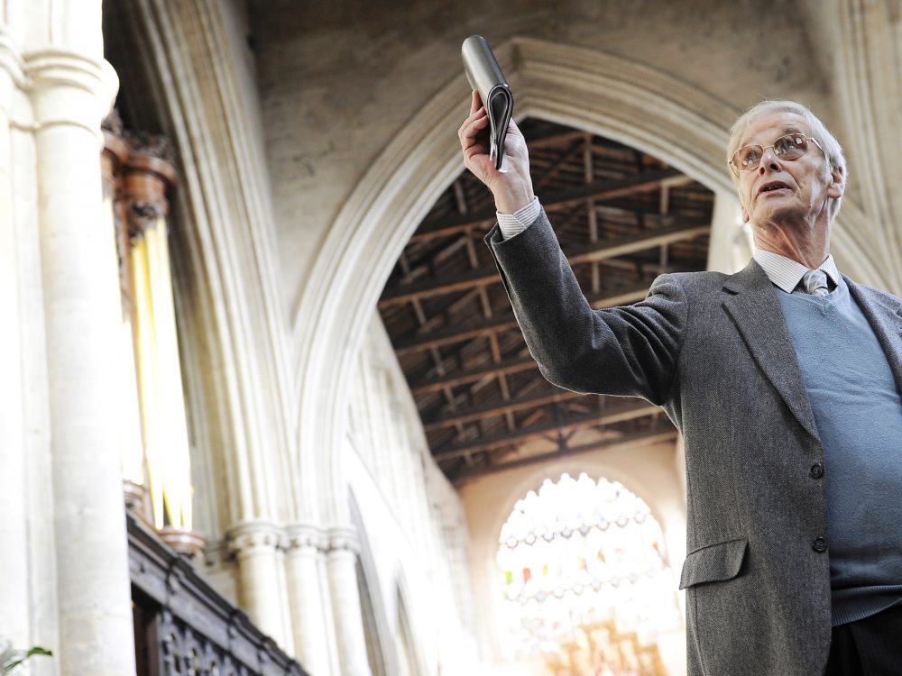 A man waving a hanseatic flag in front of King's Lynn Minster.