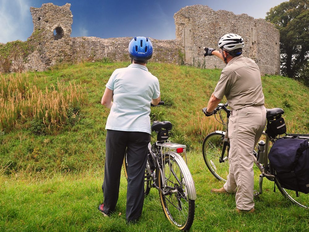 A couple looking through a hide and holding binoculars at RSPB Titchwell Marsh Nature Reserve in West Norfolk.