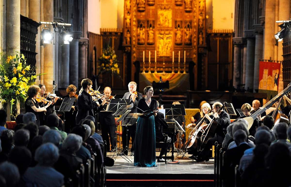 A singer standing in front of an orchestra as a part of King's Lynn Festival