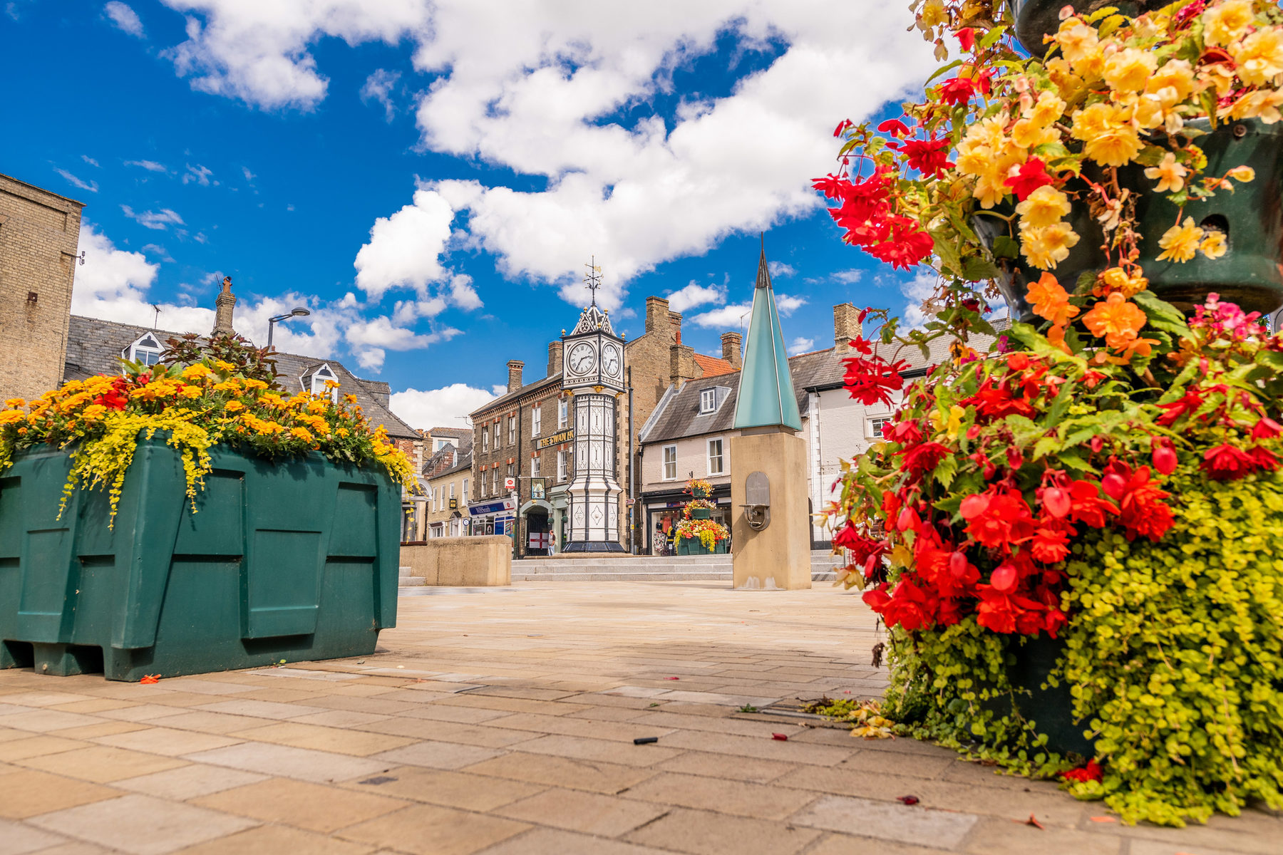 Downham Market Town Square. Standing tall in the town centre is Downham Market's black and white town clock. Vibrant flower pots surround the square.