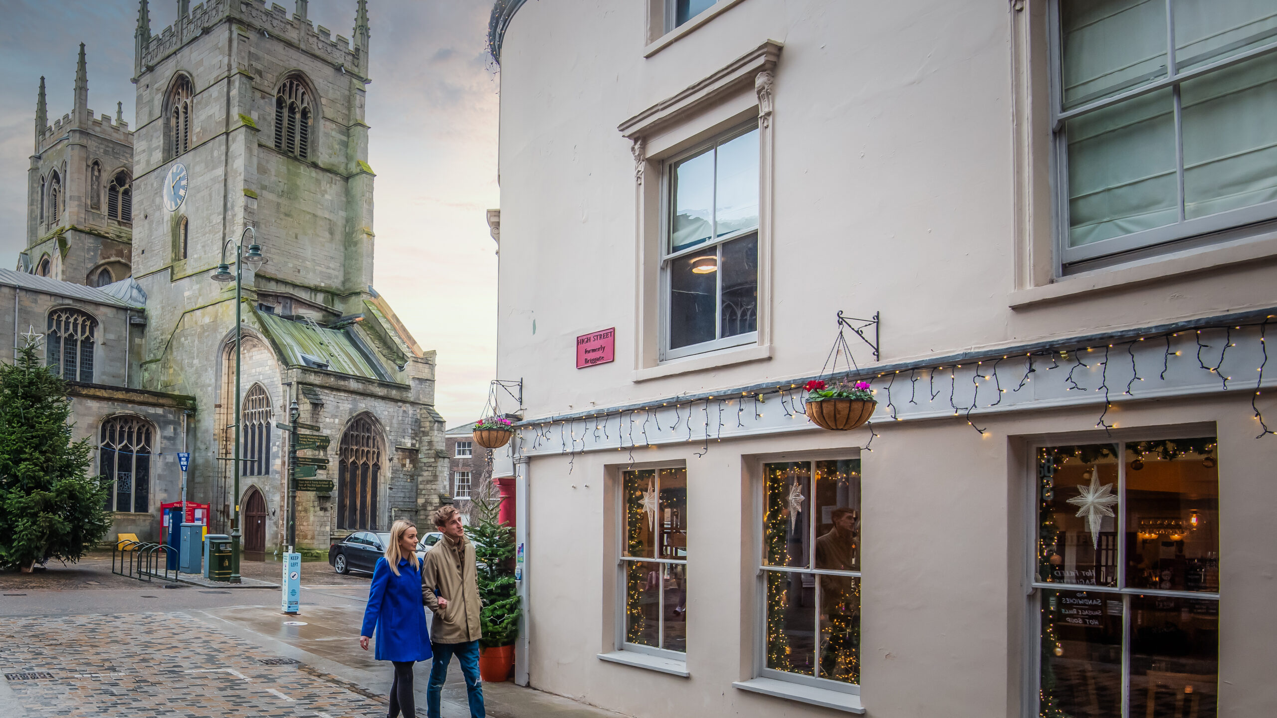 A couple walking passed The Wenns public house in King's Lynn which is lit up with Christmas lights