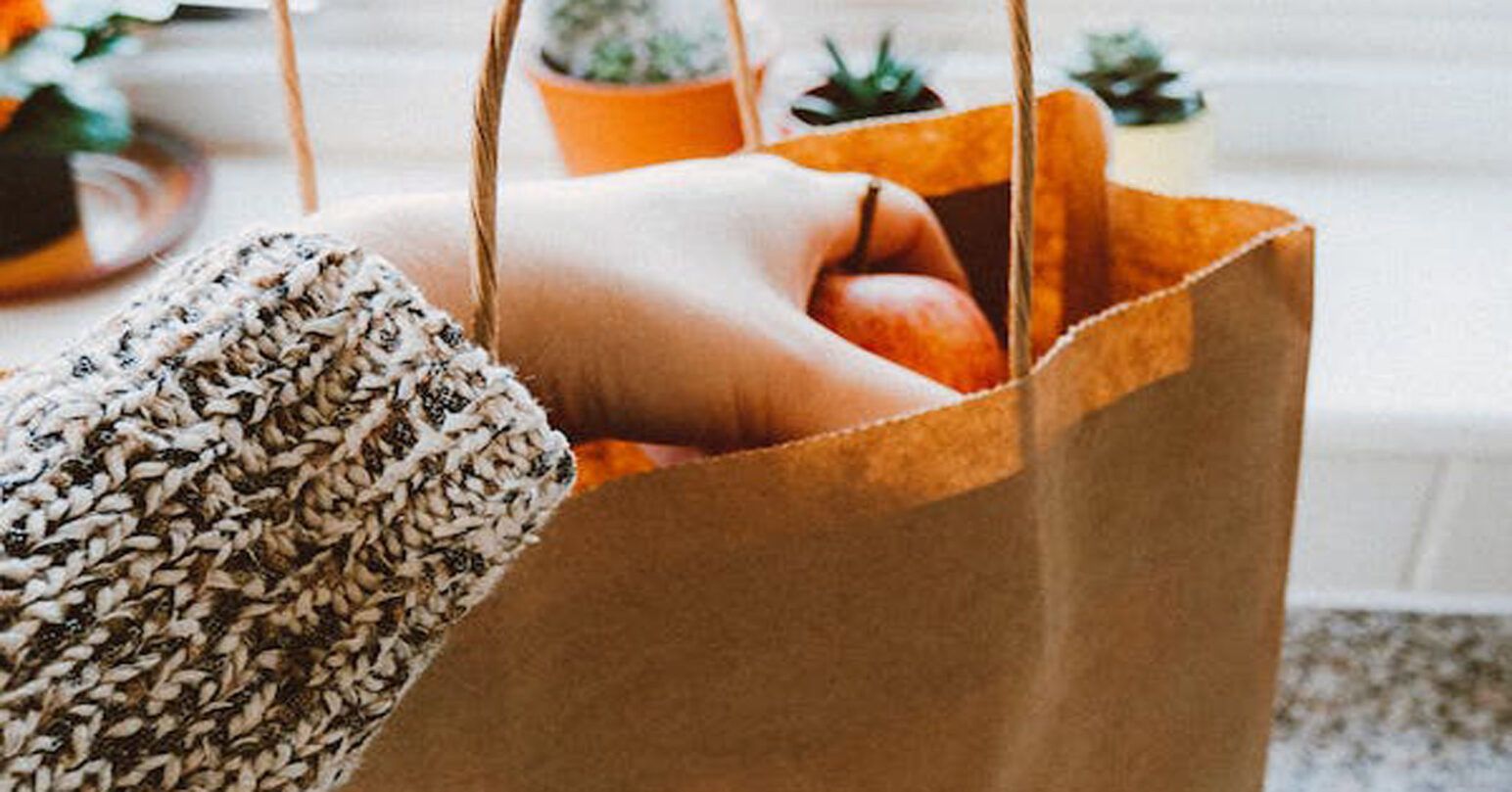 A person pulling an apple from a paper bag