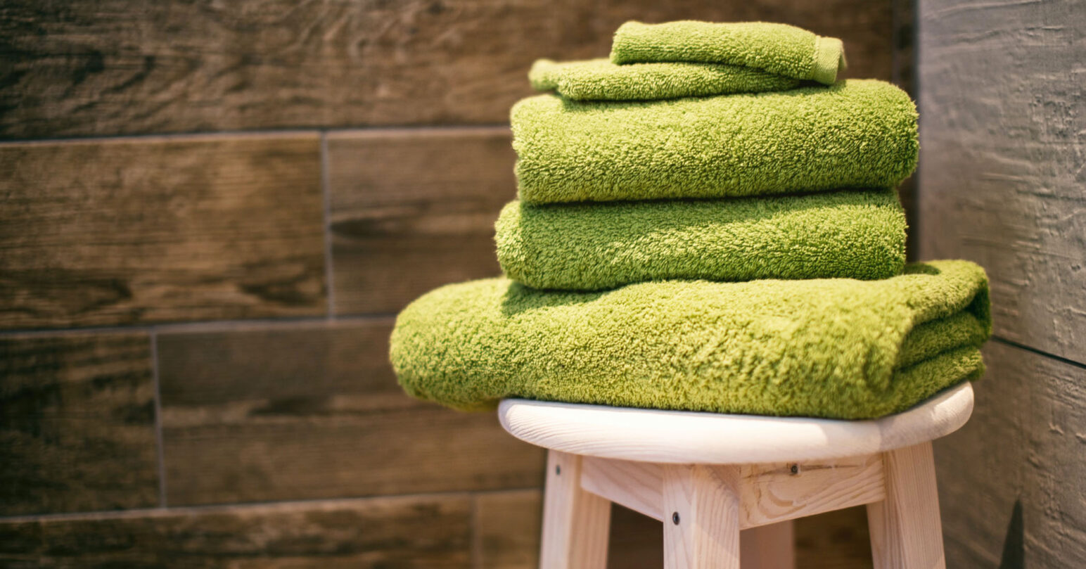 Reusable green bath towels on a wooden stool