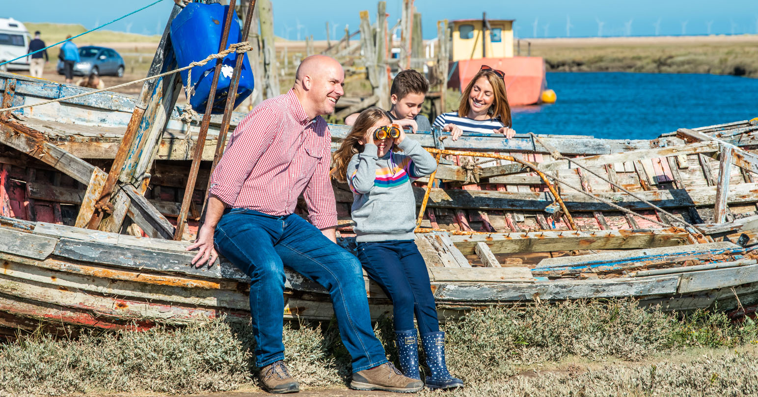 A family birdwatching. A father is watching his daughter look through yellow binoculars.