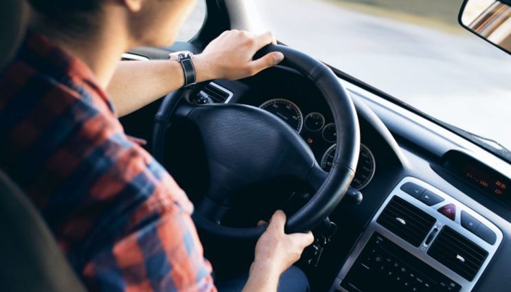 A woman holding a steering wheel inside a car.