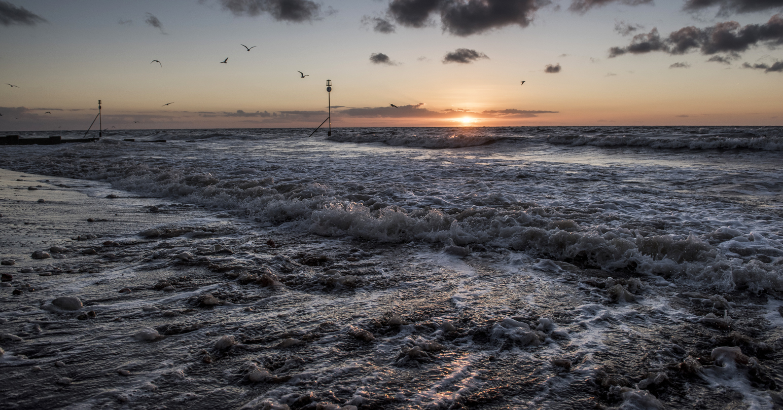 The sun setting over the waves at Hunstanton Beach.