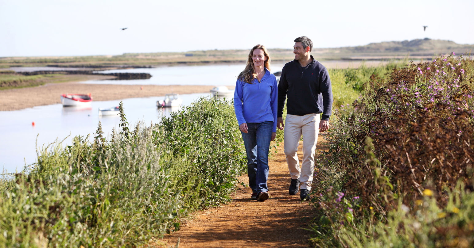 Couple walking along Burnham Overy Staithe, West Norfolk.