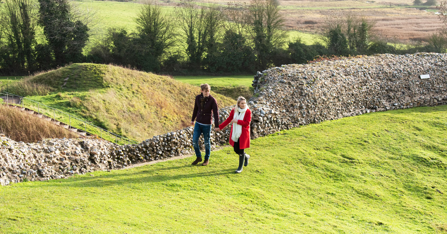 A couple holding hands walking through Castle Acre ruins, West Norfolk.