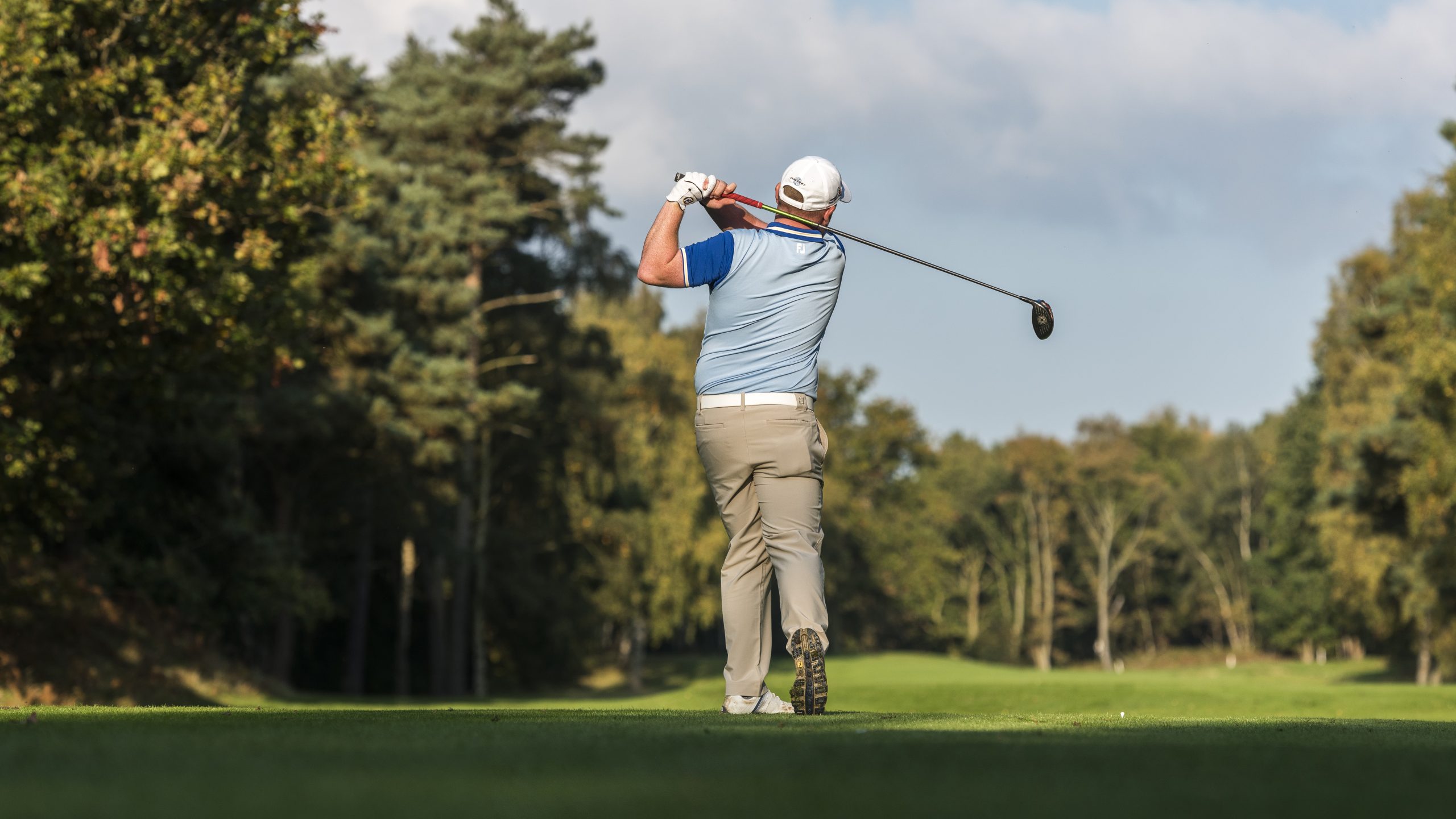 A man swinging a golf club at a golf course in west Norfolk.