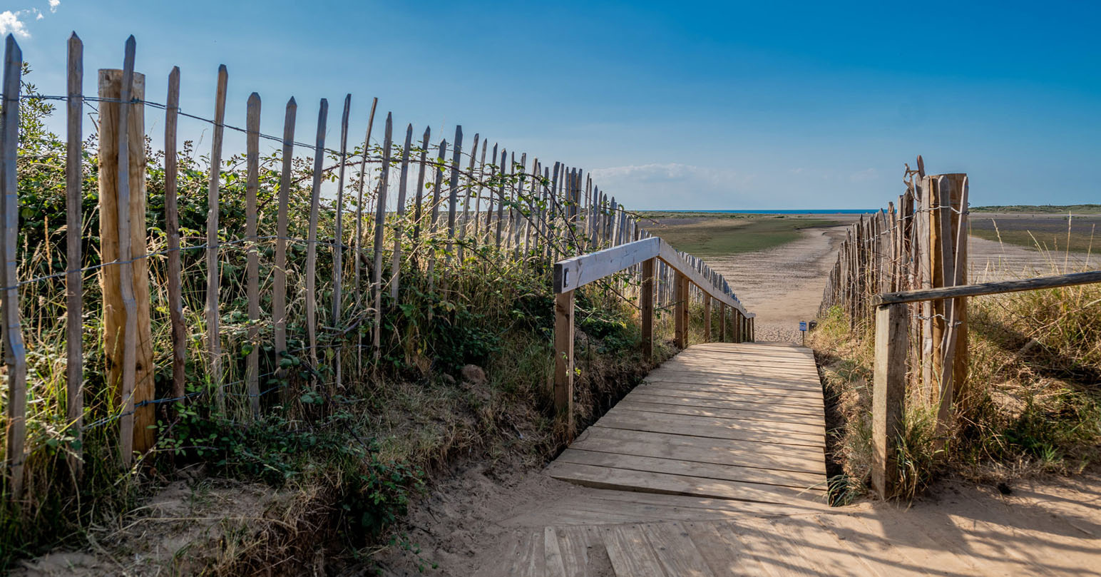 Wooden walkway towards Holkham Beach at Holkham National Nature Reserve in West Norfolk.