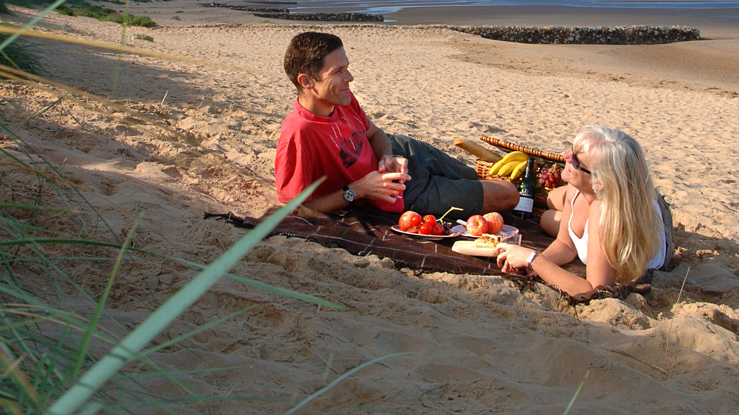 A couple enjoying a picnic hamper on a west Norfolk beach.