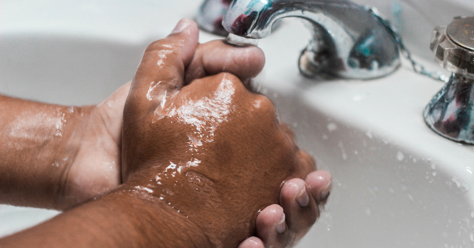 A man washing his hands under a tap.