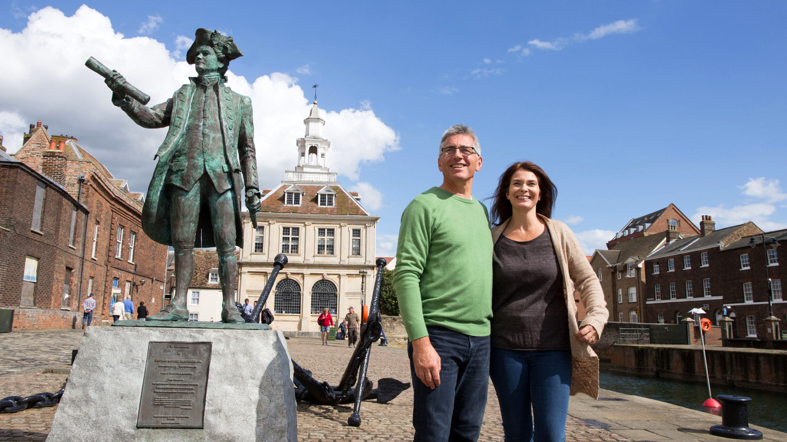 A couple standing beside the Captain Vancouver Statue on Purfleet Quay, King's Lynn.
