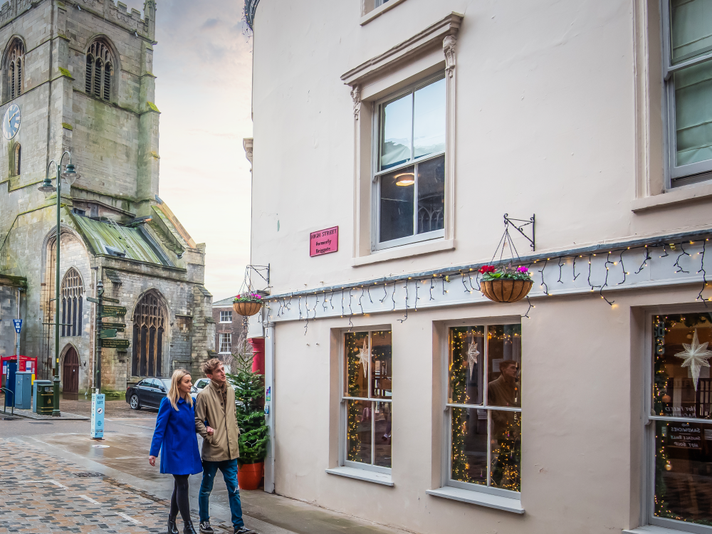 A family of three holding hands and walking through Burnham Overy in West Norfolk.